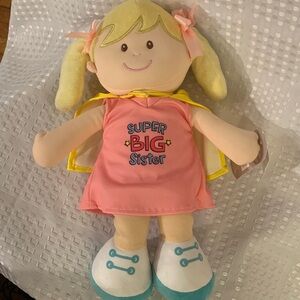 GANZ Baby Super Big Sister plush doll in pink dress and yellow cape. 15 in. tall